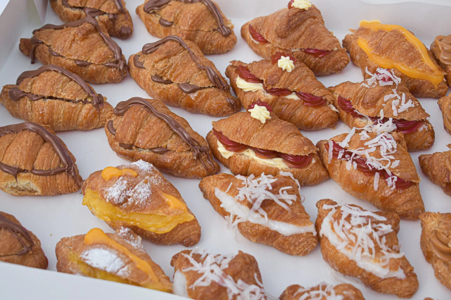 Caja de mini croissants surtidos con distintos rellenos y decoraciones