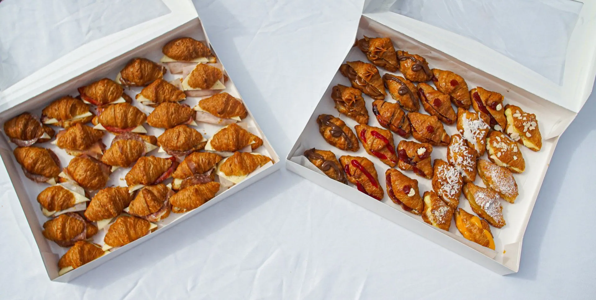 Dos cajas de croissants surtidos, dulces y salados, listas para un evento