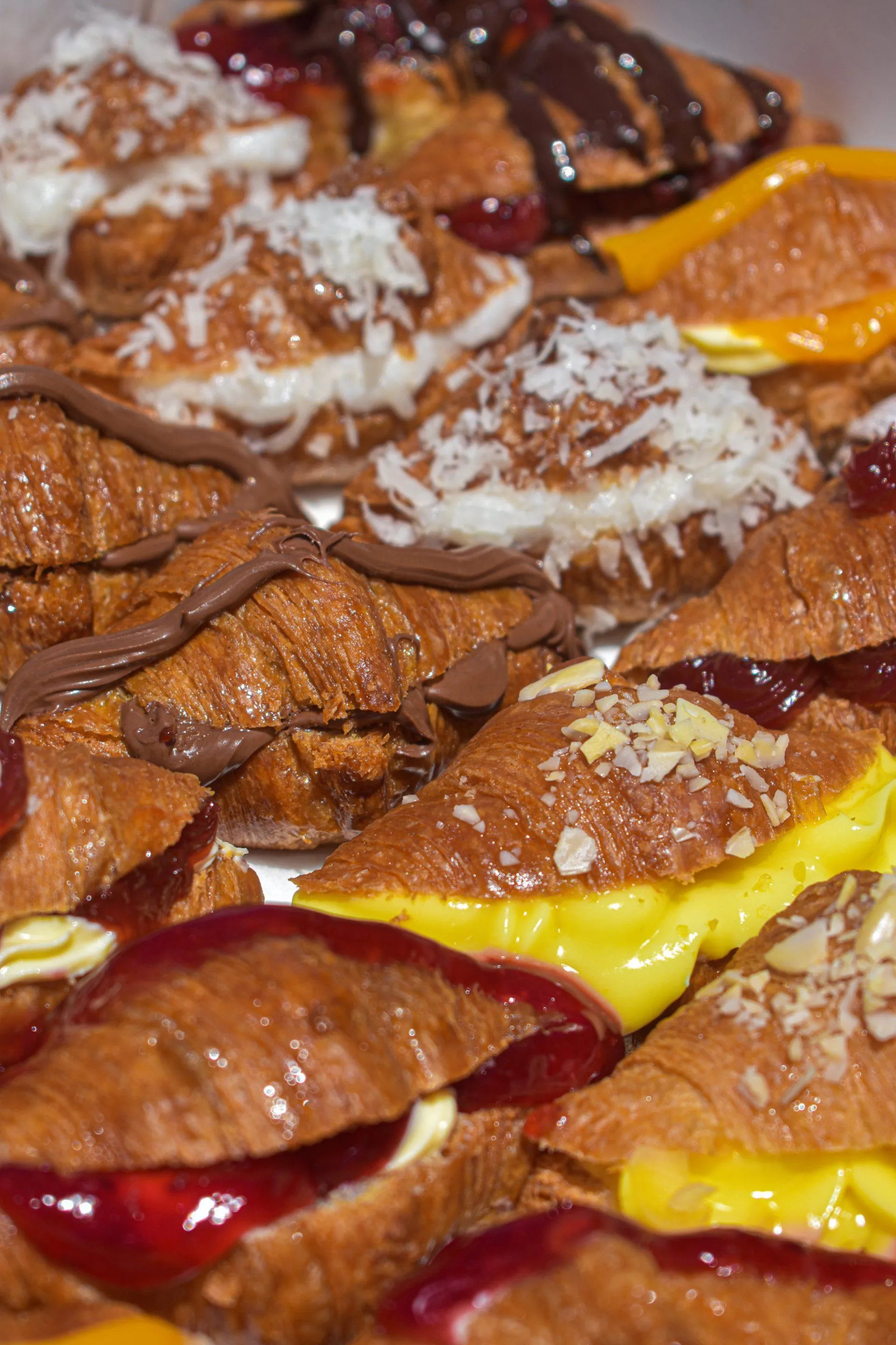Detalle de croissants rellenos surtidos: coco, chocolate, dulce de leche y crema